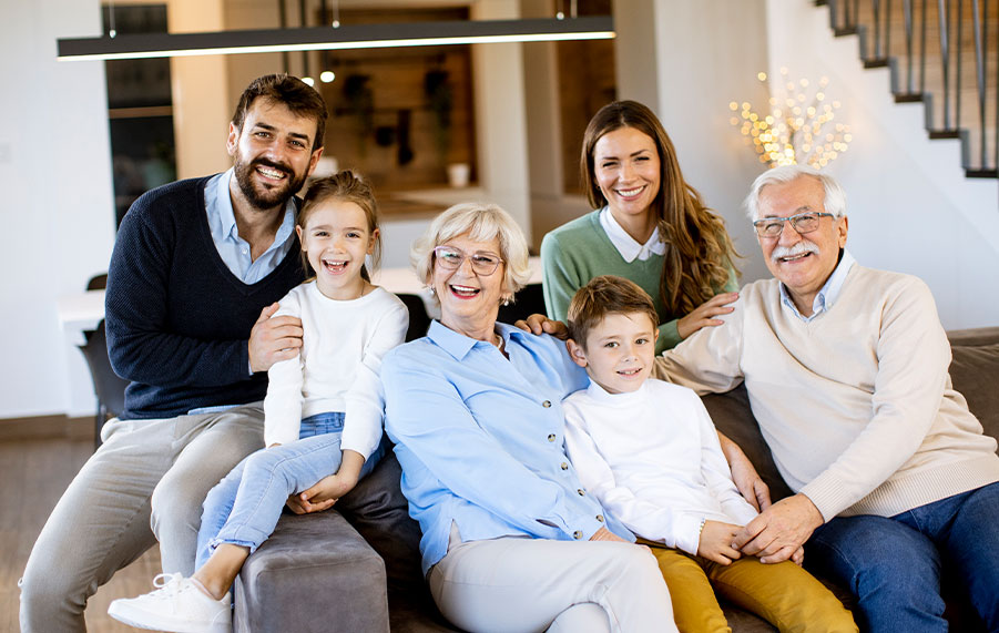 Mehrgenerationenfamilie sitzt gemeinsam im Wohnzimmer – symbolisiert das Familienmodell von WOBITA für Eigentumsübertragungen mit Wohnrecht